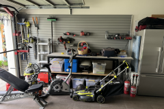 A lawnmower and mixed tools organised on shelving alongside StoreWALL slatwall panels
